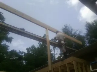 Carpenter setting a ridge beam over a new addition frame — Ice Dam Removal by Roofing Brothers in Donahue