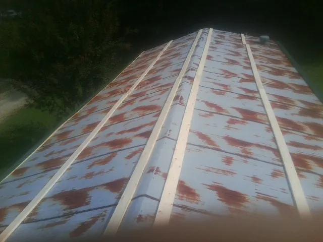 Rusted metal roof panels with new wood purlins before replacement — Storm Damage Roof Repair in Donahue by Roofing Brothers