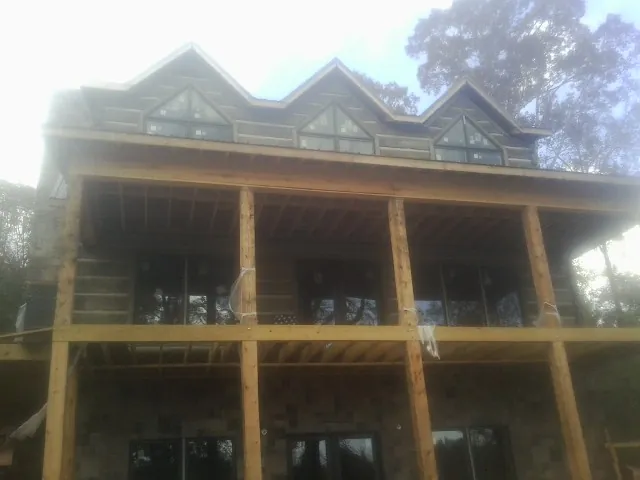 Dormers and porch framing on a large log home under construction — Roof Coating work by our crew in Donahue