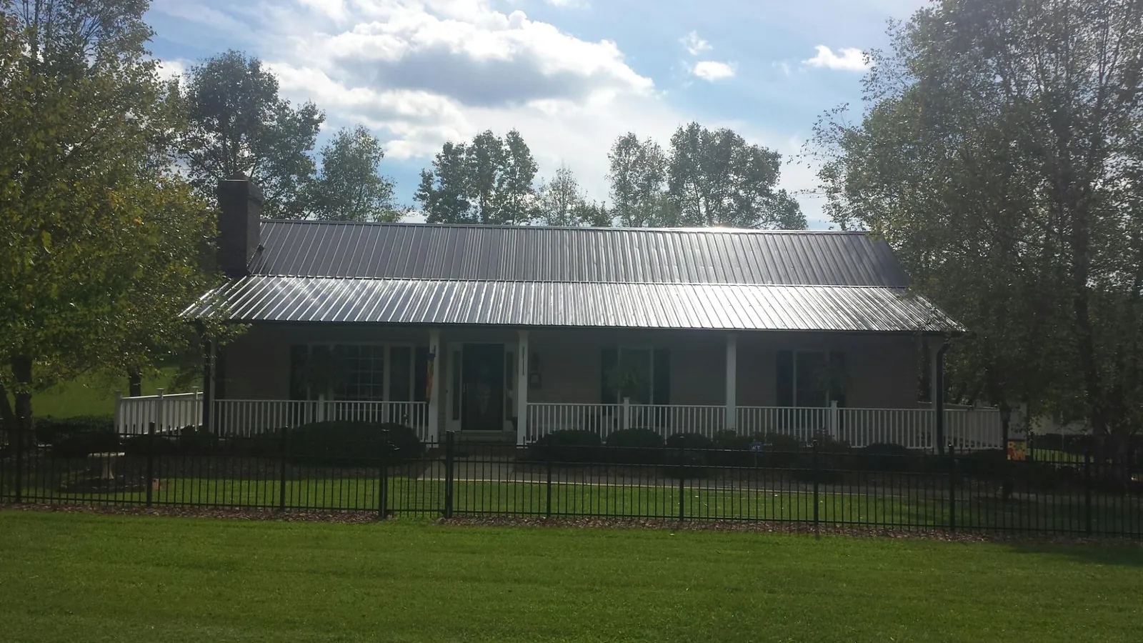 Gray metal roof on a brick ranch with a full width front porch in Donahue