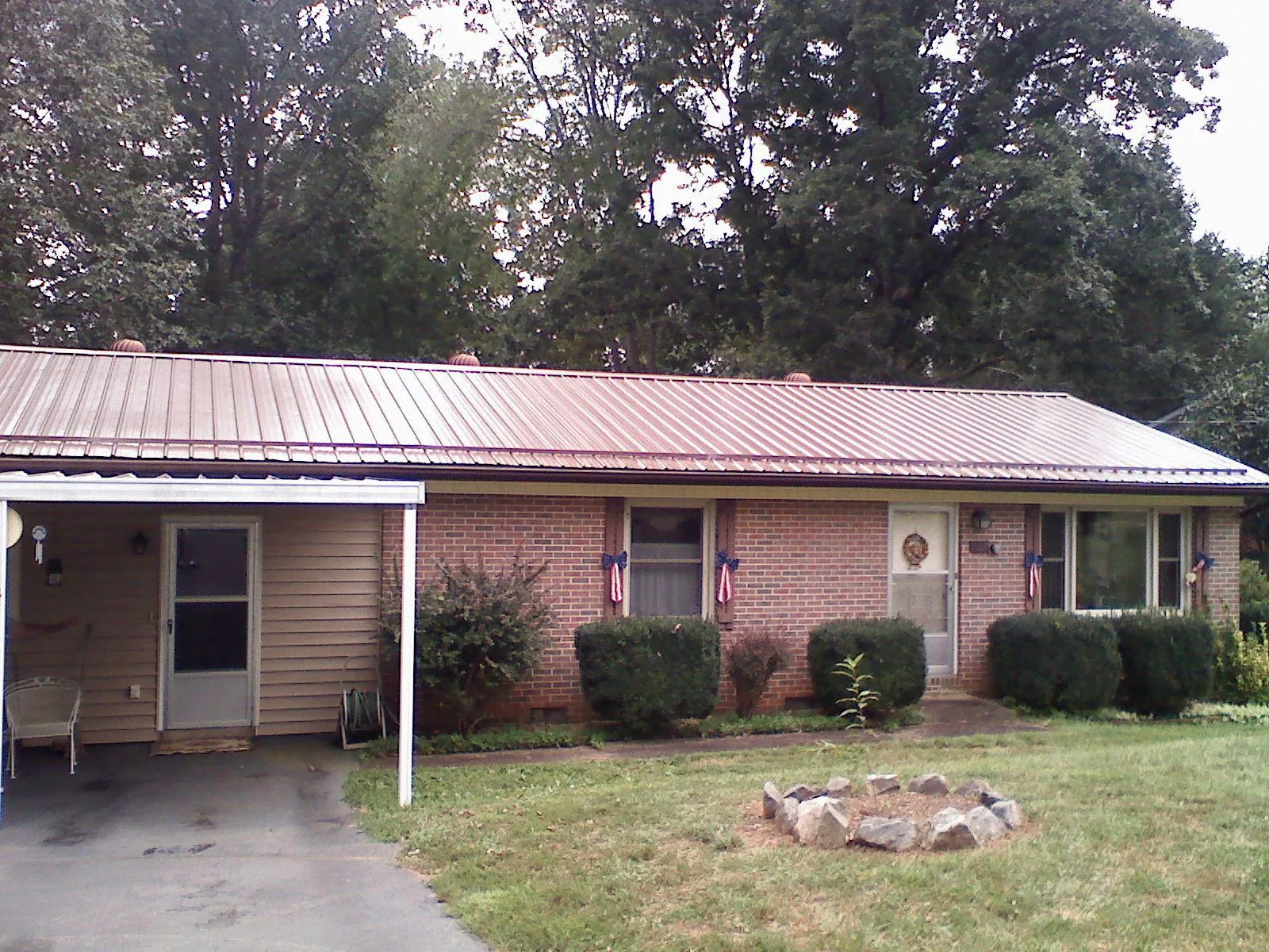 Bronze metal roof and carport on a brick ranch home — Roof Repair work by our crew in Donahue